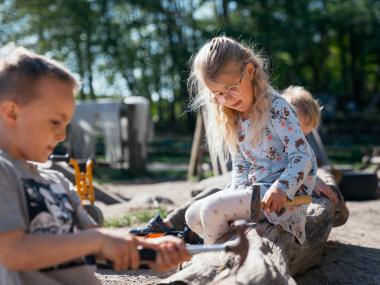 Børn der koncentreret hamrer søm i et bræt